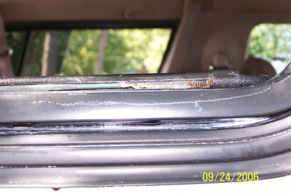 Close-up of vehicle window seal and track with rust, date stamp 09/24/2006.
