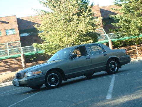 2000 Ford Crown Victoria - Gray 2000 Ford Crown Victoria parked outdoors near a brick building.