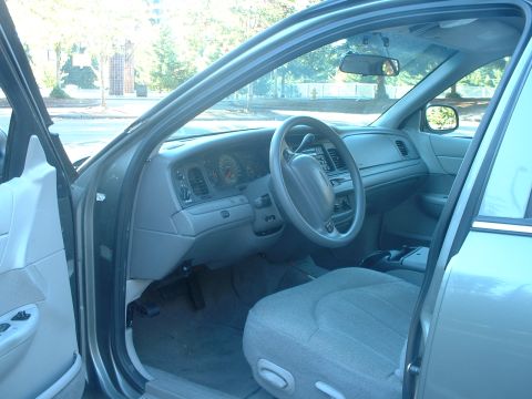 2000 Ford Crown Victoria - The interior of a sedan is shown, the dashboard, steering wheel, and seats with the driver's door ajar.
