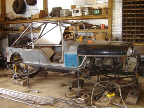 1992 Ford Bronco - This Jeep CJ-6 body is being modified with a roll cage and has its engine exposed in a workshop.