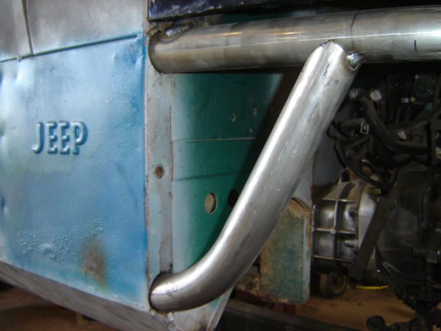 Jeep fender with roll cage tubing, blue and green paint, rust, and engine components visible