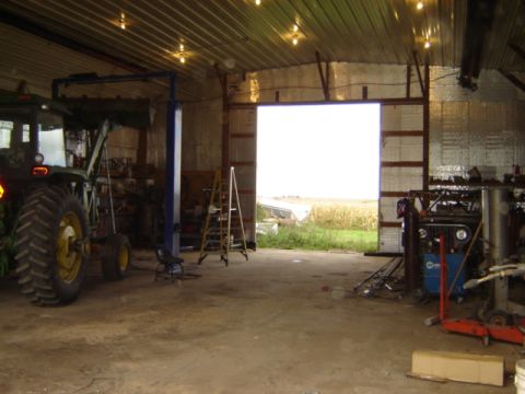 1992 Ford Bronco - Barn interior with farm equipment and a vehicle chassis visible, leading out to a field.