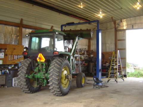 1992 Ford Bronco - A green tractor with a front loader is parked inside a garage next to a vehicle lift.