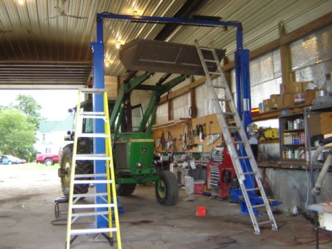 1992 Ford Bronco - A green tractor with a front loader is positioned in a workshop, with ladders and tools around it.