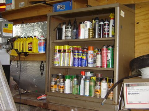 1992 Ford Bronco - A garage shelf is stocked with numerous automotive fluids and spray cans, including oil bottles and lubricants.