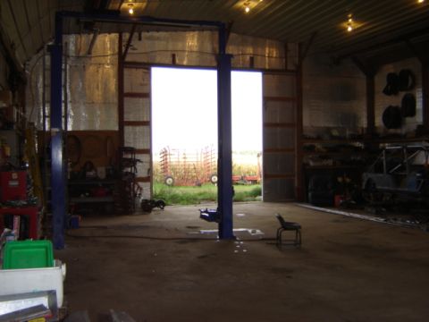 1992 Ford Bronco - Interior of a garage with a car lift and farm equipment visible through the open doors.