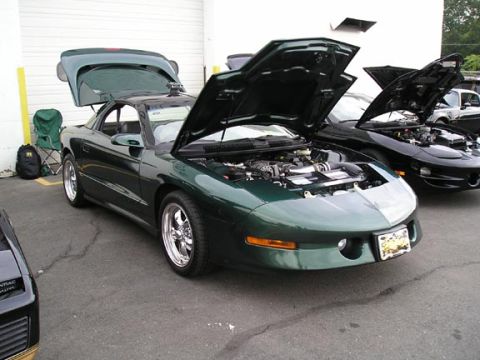 1994 Pontiac Trans Am - A green Pontiac Firebird is parked with its hood and trunk open, revealing its engine and interior.