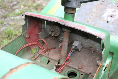 1987 Ford Bronco - The exposed wiring and ignition switch assembly of a green lawn tractor is shown in this close-up.