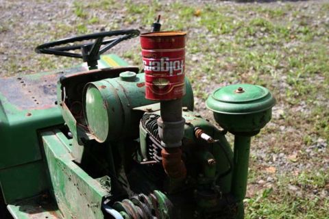 1987 Ford Bronco - A close-up view of a green lawn tractor engine, a makeshift muffler extension made from a Folgers coffee can.