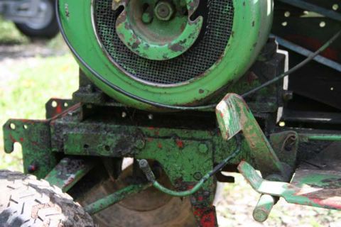 1987 Ford Bronco - Close-up of a green tractor's engine and chassis, showing mechanical components and a tire, covered in mud and rust.