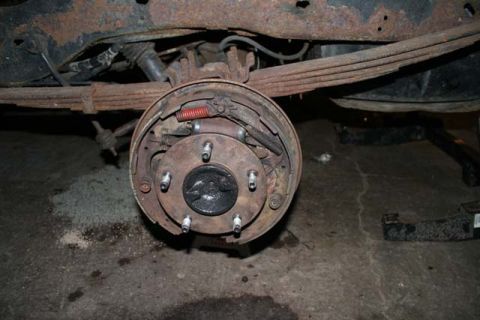 1987 Ford Bronco - Close-up of a vehicle's rusty rear drum brake assembly and suspension.