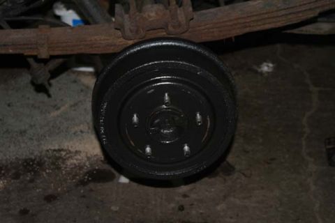 1987 Ford Bronco - Close-up view of a rear drum brake assembly, showing the painted drum and suspension parts.