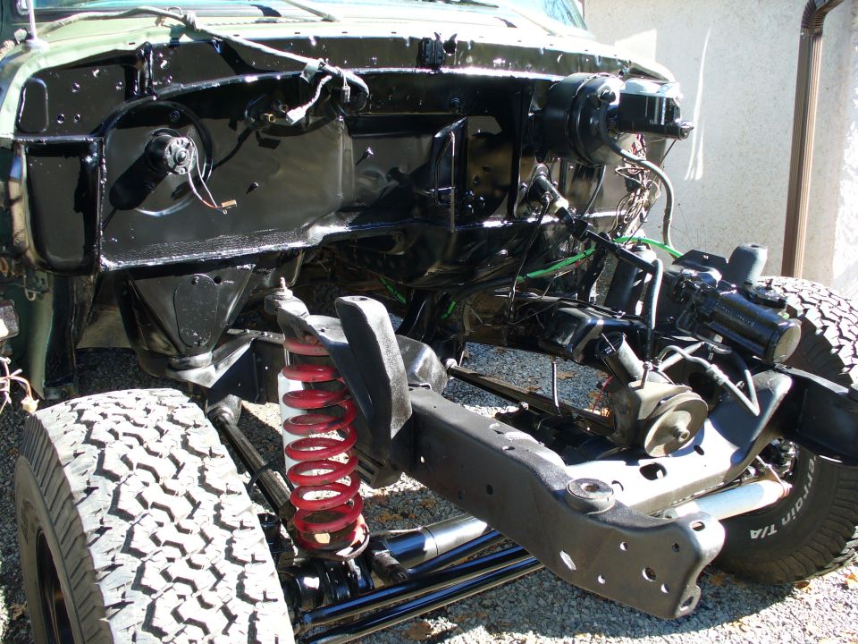 Green 4x4 with front sheetmetal off showing black engine bay, red coil spring and radius arm
