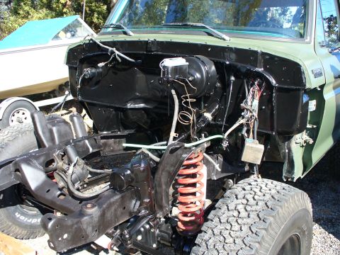 1978 Ford Bronco - The engine bay of a green vehicle is shown with the front end disassembled, revealing the chassis and suspension.