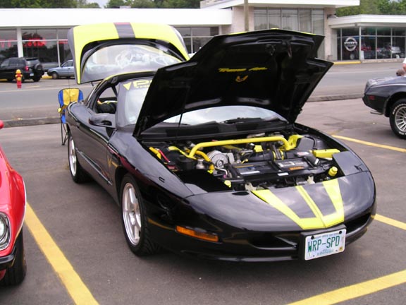 Black 1994 Pontiac Trans Am with yellow stripes, hood open, showing engine