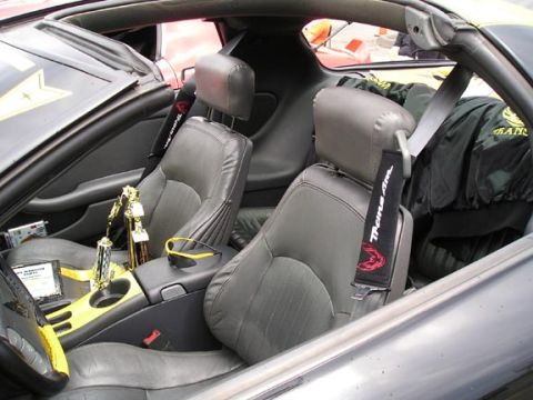 1994 Pontiac Trans Am - The interior of a 1994 Pontiac Trans Am shows trophies and a jacket, with the 'Trans Am' logo visible on the seatbelt cover.