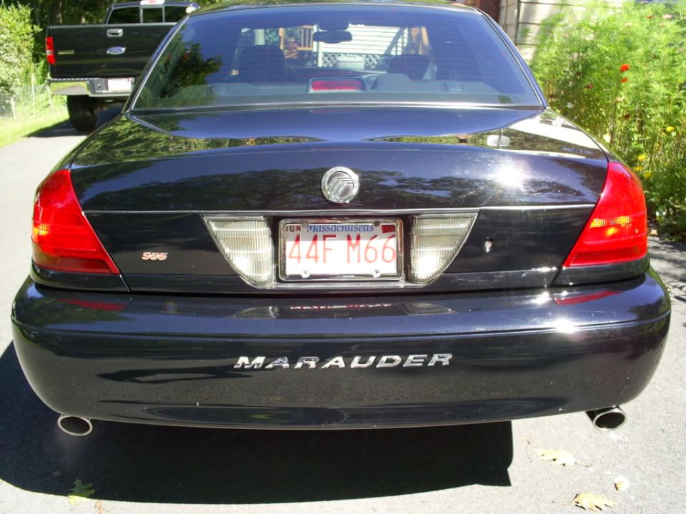 Black 2003 Mercury Marauder sedan rear view, Massachusetts license plate 44F M66, with a black pickup truck behind it