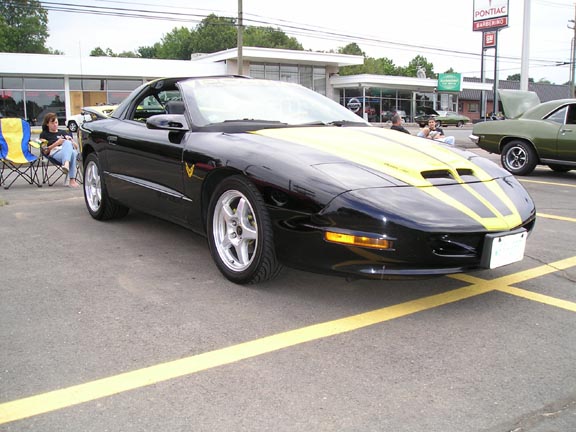 Black 1994 Pontiac Trans Am with yellow stripes parked outside