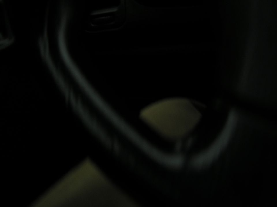 Dark interior with a blurry steering wheel and a yellow object