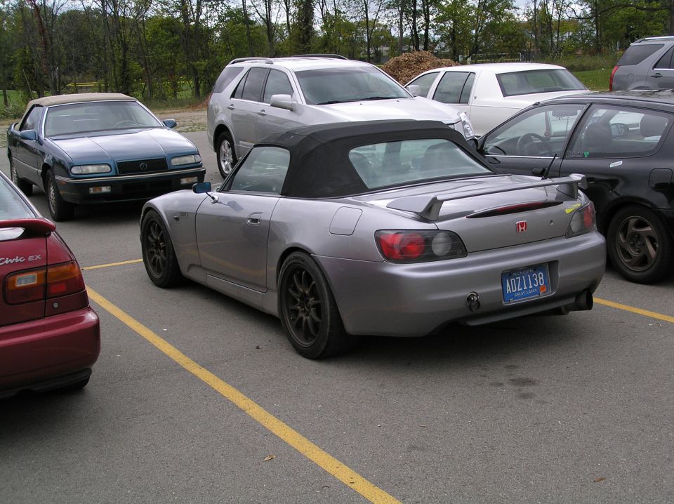 Silver Honda S2000 convertible with black soft top parked in a lot