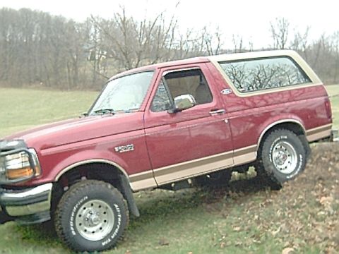 1994 Ford Bronco - Red 1994 Ford Bronco with tan side trim is shown from the front quarter angle.