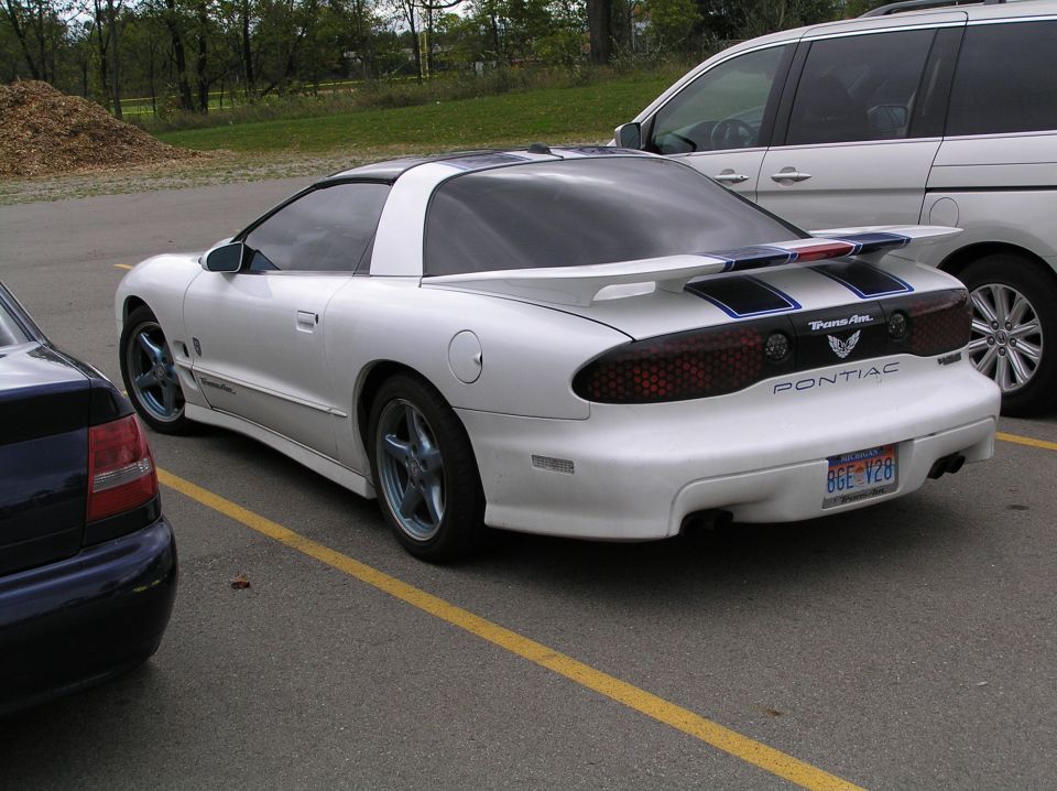 White Pontiac Trans Am coupe with blue stripes parked in a lot
