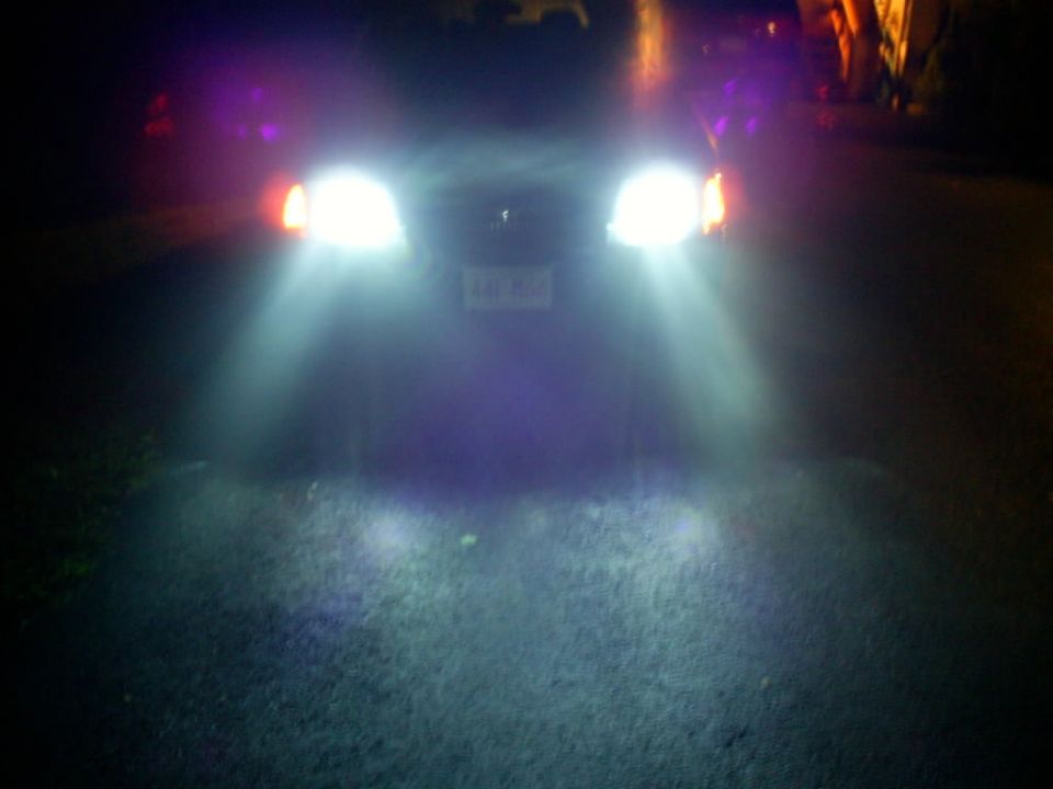 Car with bright headlights and purple accent lights at night