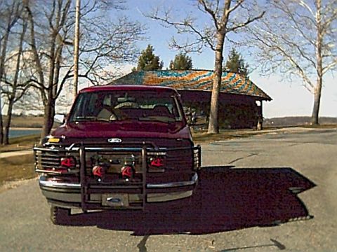 1994 Ford Bronco - This 1994 Ford Bronco is captured from the front, a prominent brush guard and a dark red paint job.