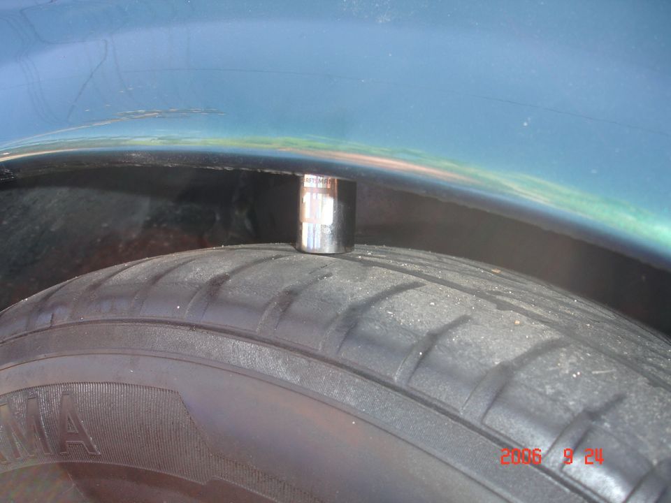 Socket wrench resting on a tire tread, with the car's fender visible above