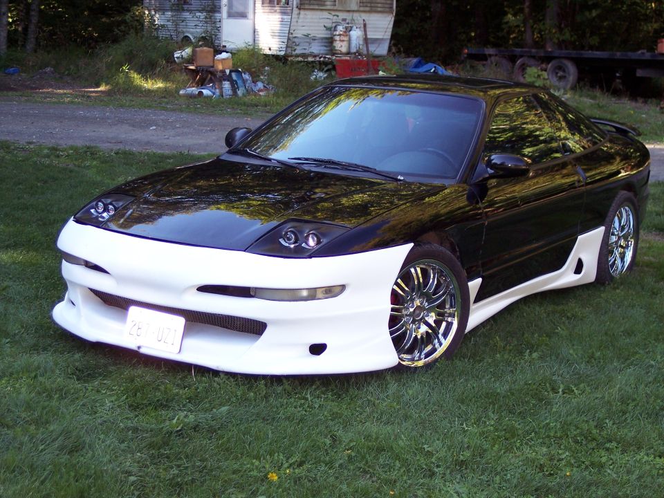 Black and white Ford Probe with custom body kit and chrome wheels parked on grass
