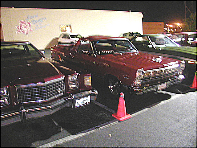 Dark red 1960s Ford Ranchero pickup at a night car show with cab lights and chrome bumper
