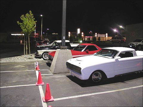 1967 Ford Ranchero - Several classic cars are parked in a lot at night, including a white coupe utility.