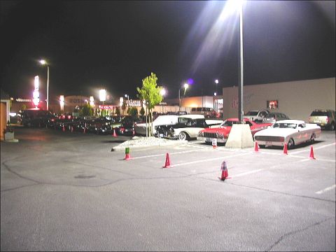 1967 Ford Ranchero - A collection of vintage automobiles are gathered in a parking lot under artificial lighting after dark.