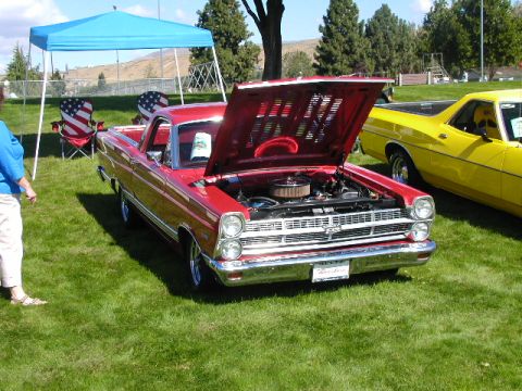 1967 Ford Ranchero - A red 1967 Ford Ranchero is displayed with its hood open, alongside another vehicle on a grassy field.