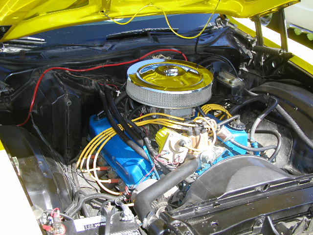 V8 engine bay with chrome air cleaner, blue valve covers and yellow plug wires in a yellow car