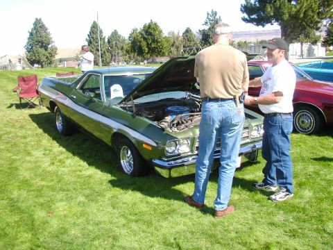 1967 Ford Ranchero - Two men examine the engine of a green 1972 Ford Ranchero parked on a grassy field.