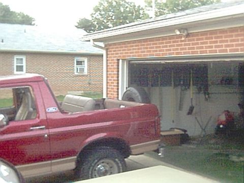 1994 Ford Bronco - This 1994 Ford Bronco, seen from a three-quarter front angle, has its top removed and is parked beside a brick garage.