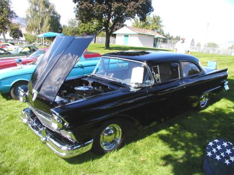 1967 Ford Ranchero - A black 1957 Ford Fairlane 500 is displayed with its hood up at an outdoor car show.