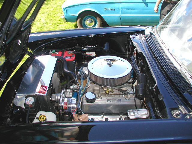 Dark blue car's V8 engine bay with chrome round air cleaner and polished valve covers