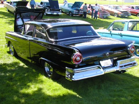 1967 Ford Ranchero - A black 1957 Ford Fairlane 500 is displayed at an outdoor car show, with other vehicles visible in the background.