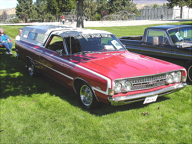 Red Ford Ranchero with white canopy and quad headlights at an outdoor car show