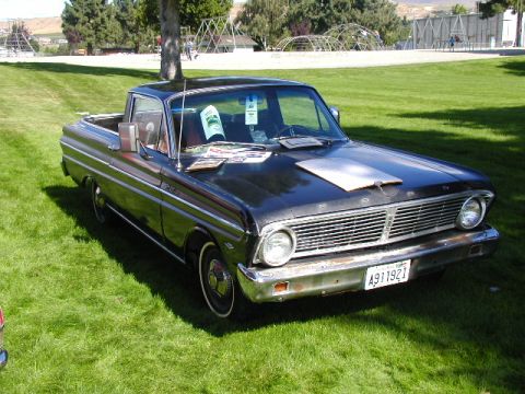 1967 Ford Ranchero - This black Ford Falcon Ranchero, likely a 1964 model, is parked on a grassy lawn with trees in the background.