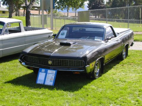 1967 Ford Ranchero - A dark green 1970 Ford Ranchero is displayed on a grassy field, with a white pickup truck to its left.