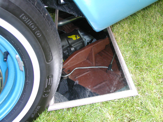 Mirror under a light blue show car reflecting its red-oxide painted undercarriage