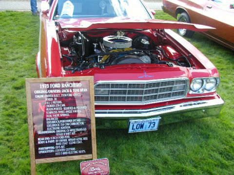 1967 Ford Ranchero - A red 1973 Ford Ranchero is displayed with its hood open, revealing the engine bay, while another vehicle is visible in the background.