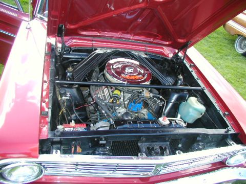 1967 Ford Ranchero - The engine bay of a 1967 Ford Ranchero reveals a V8 engine with a chrome air cleaner and red paint.