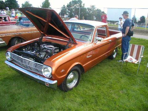 1967 Ford Ranchero - Orange 1967 Ford Ranchero on display with hood up, parked on grass next to another vehicle.