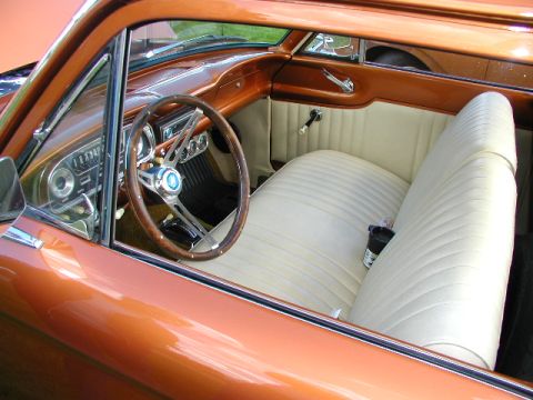 1967 Ford Ranchero - The interior of a classic car features a wood-rimmed steering wheel and a cream-colored bench seat.