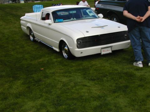 1967 Ford Ranchero - This 1967 Ford Ranchero pickup truck features a distinctive custom grille and a unique hood ornament, displayed on a grassy field.