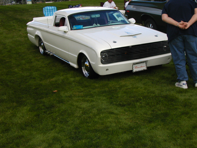 White 1960s Ford Ranchero pickup on grass, 3/4 front view, lowered on chrome wheels